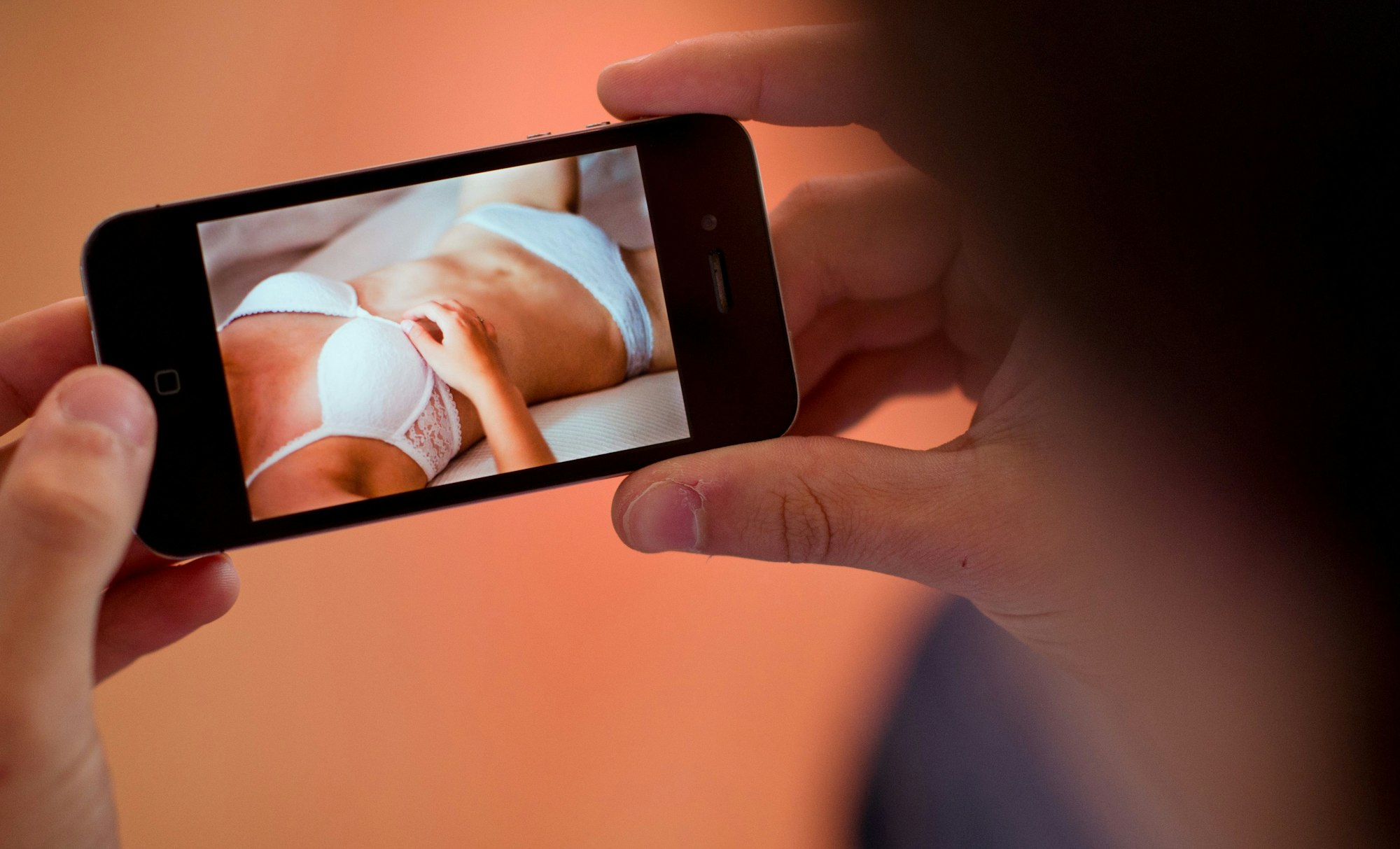 Ein junger Mann hält am 31.10.2013 in Hannover (Niedersachsen) ein Smartphone, auf dem ein erotisches Foto einer jungen erwachsenen Frau zu sehen ist.