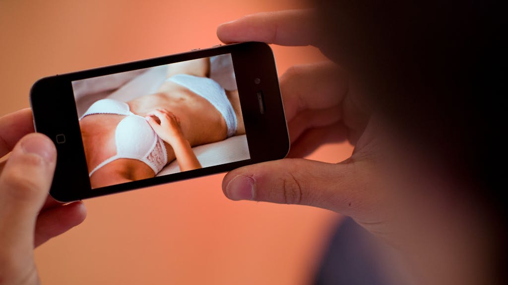 Ein junger Mann hält am 31.10.2013 in Hannover (Niedersachsen) ein Smartphone, auf dem ein erotisches Foto einer jungen erwachsenen Frau zu sehen ist.&nbsp;