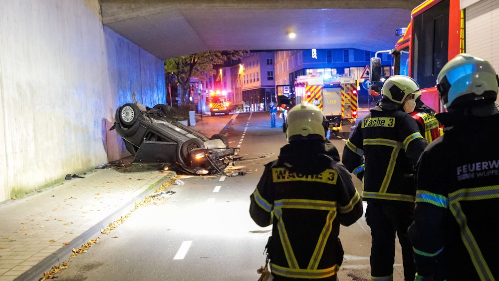 Einsatzkräfte sichern die Unfallstelle in Wuppertal. Eine 63-jährige Solingerin ist mit ihrem Cabrio sechs Meter tief von einer Brücke gestürzt und schwer verletzt worden.