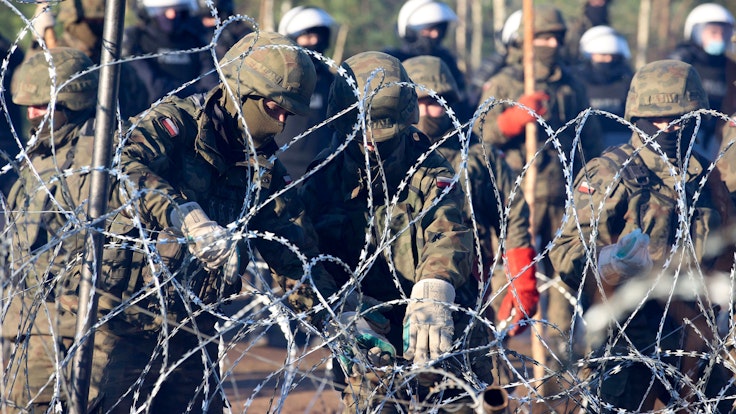 Migranten durchbrechen Grenze von Belarus nach Polen. Auf dem Foto (aufgenommen am 9. November 2021) sind polnische Polizisten und Grenzschützer zu sehen, welche am Stacheldraht stehen.