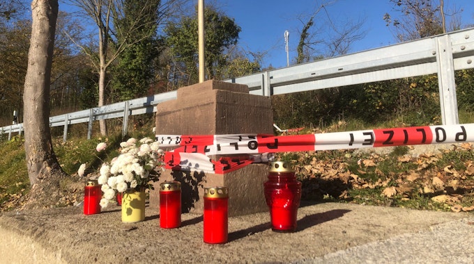 Absperrband der Polizei und Kerzen am Sockel eines Sandstein-Kreuzes in Büren-Breken, das am 11. November 2021 einen Jungen erschlagen hat.