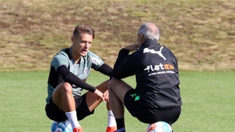 Hannes Wolf (l.) im Gespräch mit Adi Hütter (r.) von Borussia Mönchengladbach, beide sitzen auf Fußbällen auf dem Trainingsgelände am 23. September 2021.