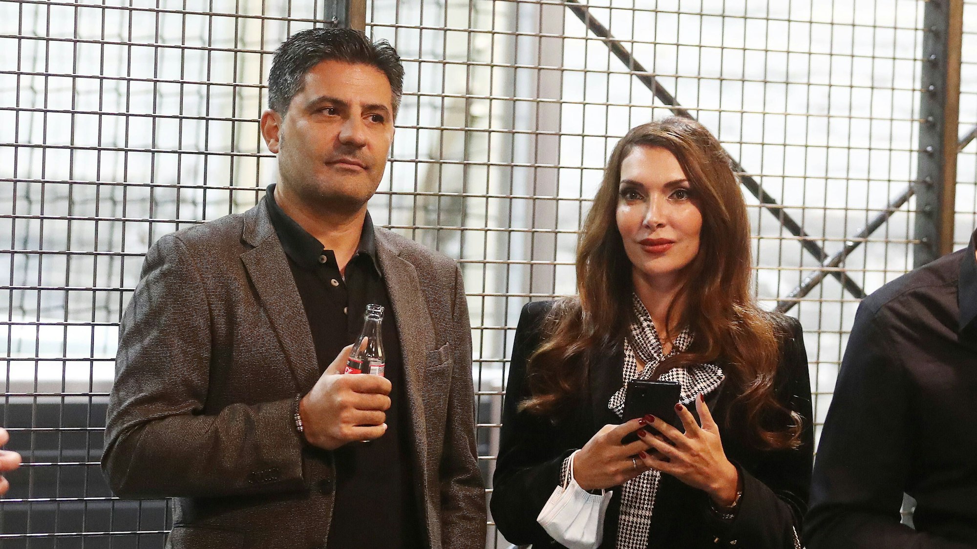 Babak Rafati steht neben seiner Frau Rouja. Er hält eine Cola-Flasche in der Hand, sie ihr Smartphone.