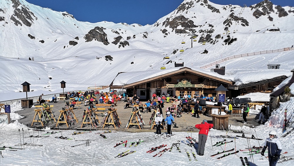 Auf dem Foto (aufgenommen am 31. März 2021) sieht man Skifahrer in Österreich auf der Terrasse einer geschlossenen Skihütte sitzen.