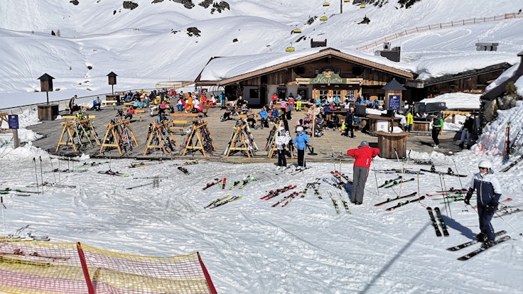 Auf dem Foto (aufgenommen am 31. März 2021) sieht man Skifahrer in Österreich auf der Terrasse einer geschlossenen Skihütte sitzen.
