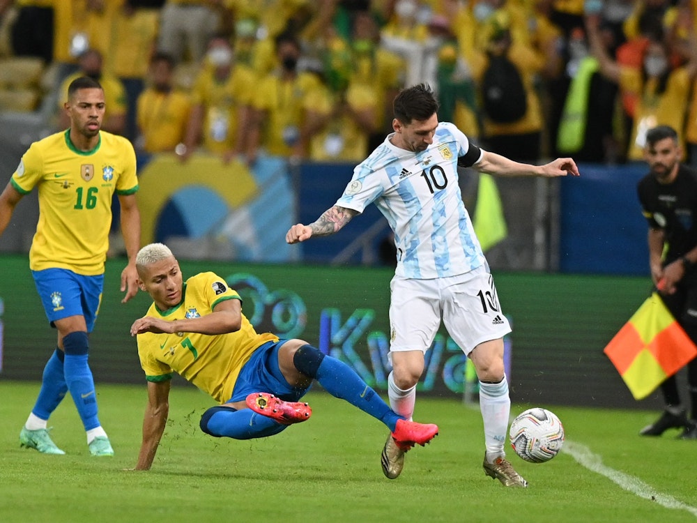 Richarlison aus Brasilien versucht Lionel Messi aus Argentinien zu stoppen, während Renan Lodi zuschaut.