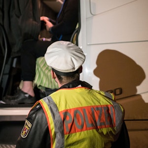 Ein Polizist steht im Februar 2019 bei der Kontrolle eines Lkw-Fahrers an dem Fahrzeug.