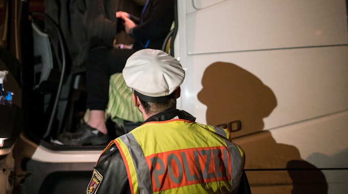 Ein Polizist steht im Februar 2019 bei der Kontrolle eines Lkw-Fahrers an dem Fahrzeug.