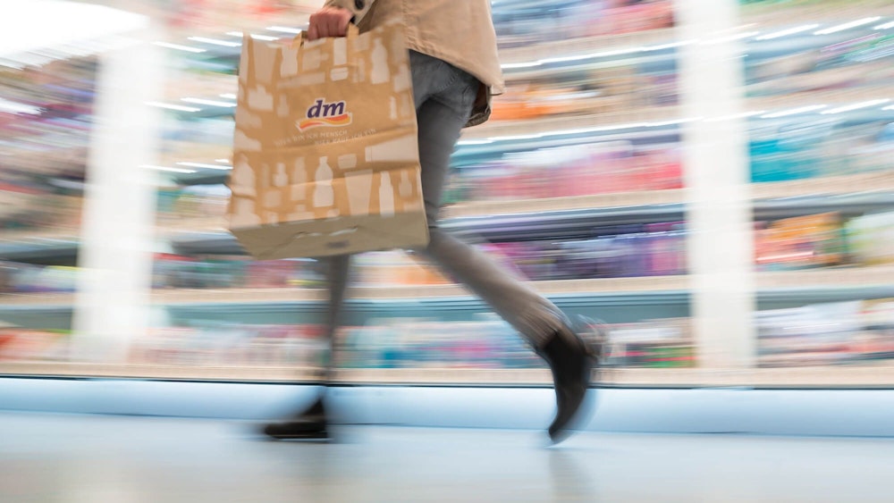 Auf dem Symbolfoto (aufgenommen am 11. November 2021) sieht man eine Frau mit dm-Tragetasche durch das Geschäft gehen.