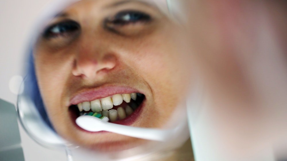 Auf dem Symbolfoto (aufgenommen am 11. März 2013) putzt sich eine Frau mit einer elektrischen Zahnbürste die Zähne.