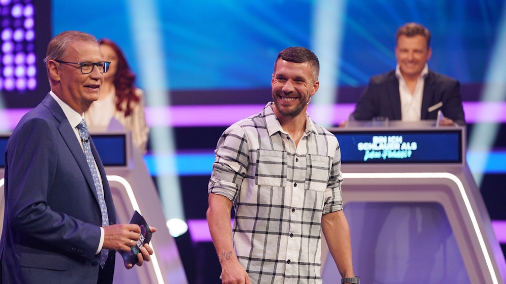 Moderator Günther Jauch und Lukas Podolski stehen in der RTL-Show „Bin ich schlauer als Lukas Podolski?“ nebeneinander.