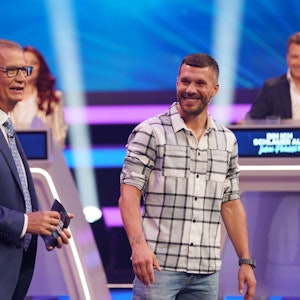 Moderator Günther Jauch und Lukas Podolski stehen in der RTL-Show „Bin ich schlauer als Lukas Podolski?“ nebeneinander.