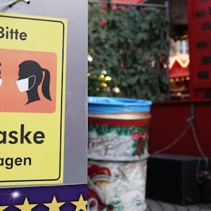 Auf einem Desinfektionsmittelspender am Düsseldorfer Weihnachtsmarkt hängt ein Schild mit der Aufschrift «Bitte Maske tragen».