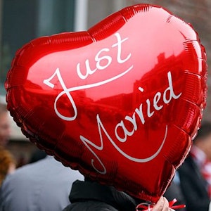 Eine Frau hält einen Ballon mit der Aufschrift „Just Married“ in der Hand.