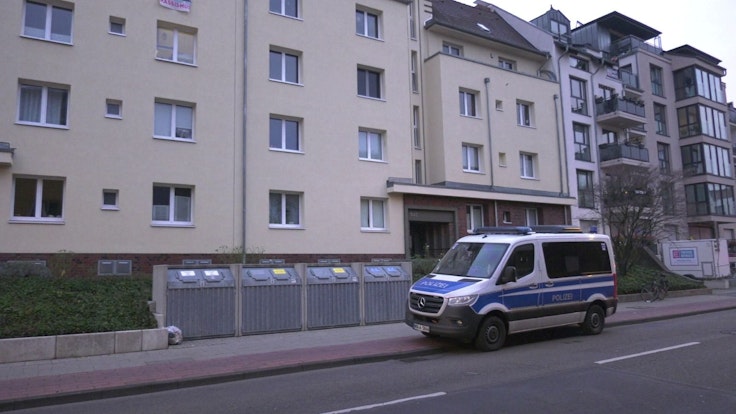 Ein Polizeifahrzeug steht vor einem Mehrfamilienhaus in Köln.