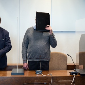 Der angeklagte katholische Priester hält sich im Gerichtssaal eine Mappe vor das Gesicht.