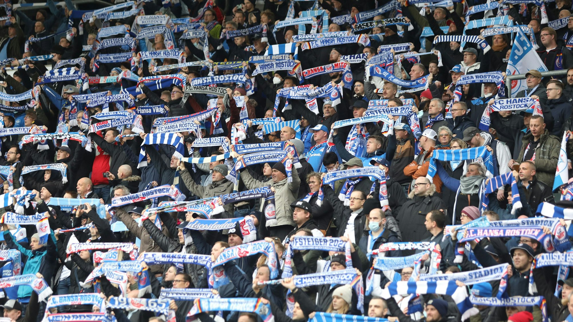 Fans von Hansa Rostock halten ihre Schals im Ostseestadion hoch.