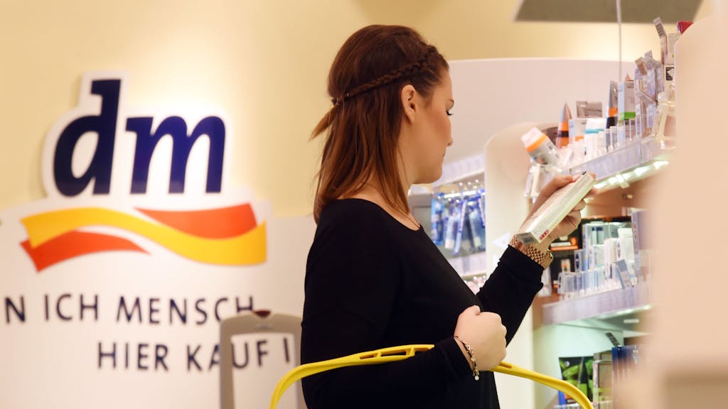 Eine Frau steht in einer Filiale der Drogeriemarktkette dm am 20.10.2015 in Karlsruhe (Baden-Württemberg) mit einem dm Einkaufskorb an einem Regal. Am 22.10.2015 findet in Karlsruhe die Jahres-Pressekonferenz des Drogeriekonzerns statt. Foto: Uli Deck/dpa (zu lsw Vorausmeldung: «Jahres PK DM Markt» vom 22.10.2015) ++ +++ dpa-Bildfunk +++