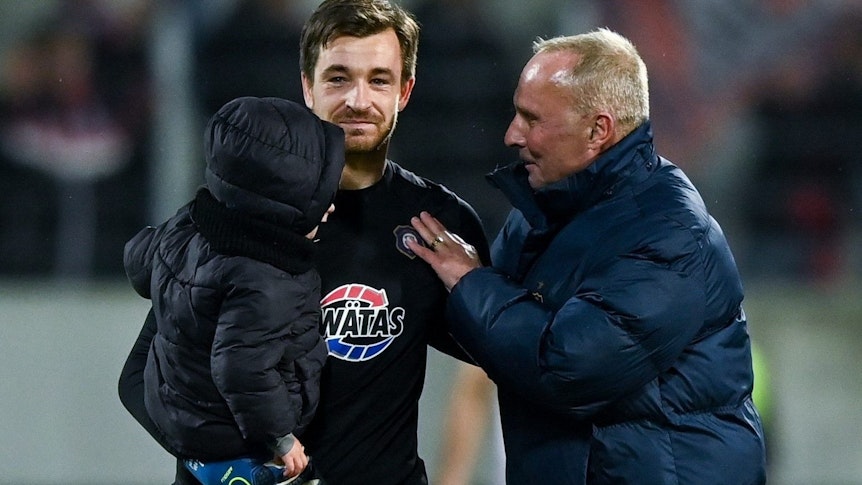 Aues Torhüter und Kapitän Martin Männel mit Kind auf dem Arm (l) und Aues Präsident Helge Leonhardt sprechen nach dem Spiel.