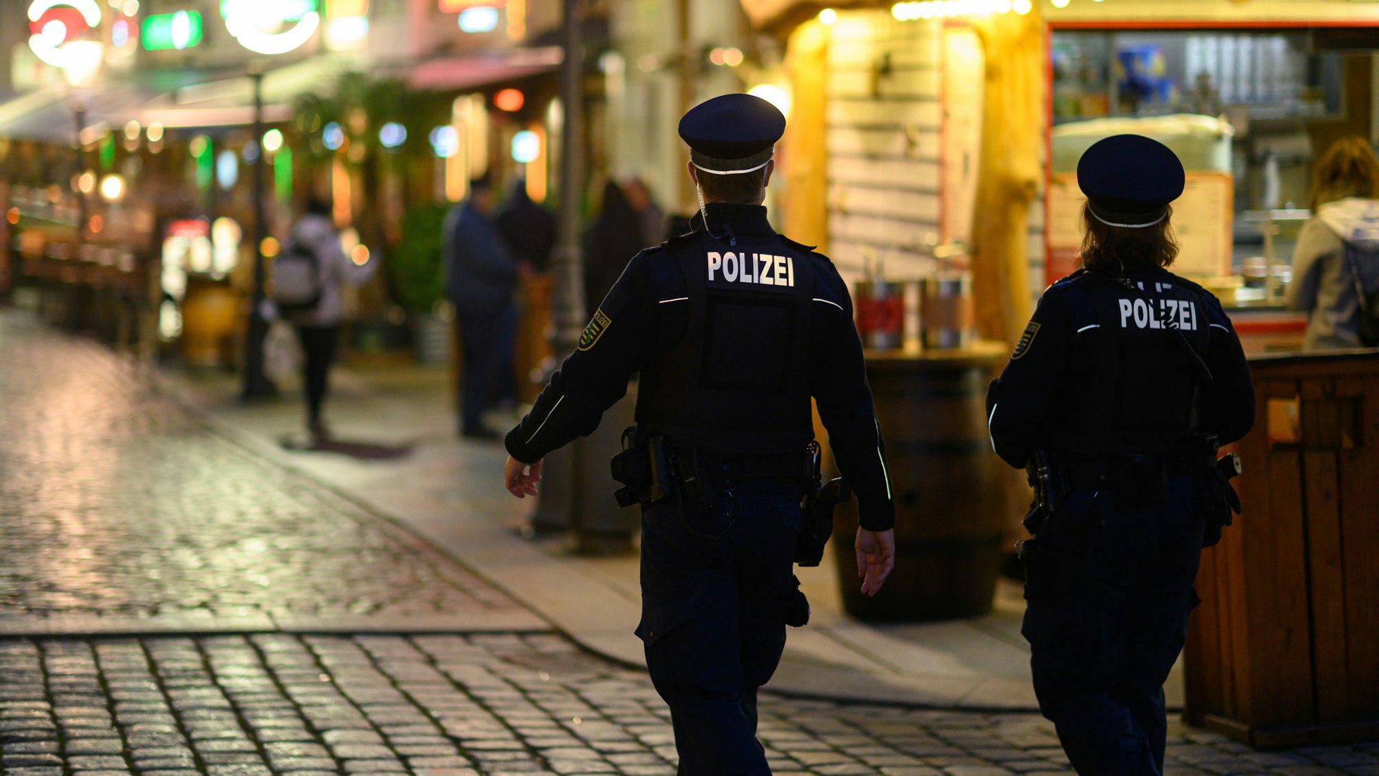 Polizisten gehen an Restaurants entlang.
