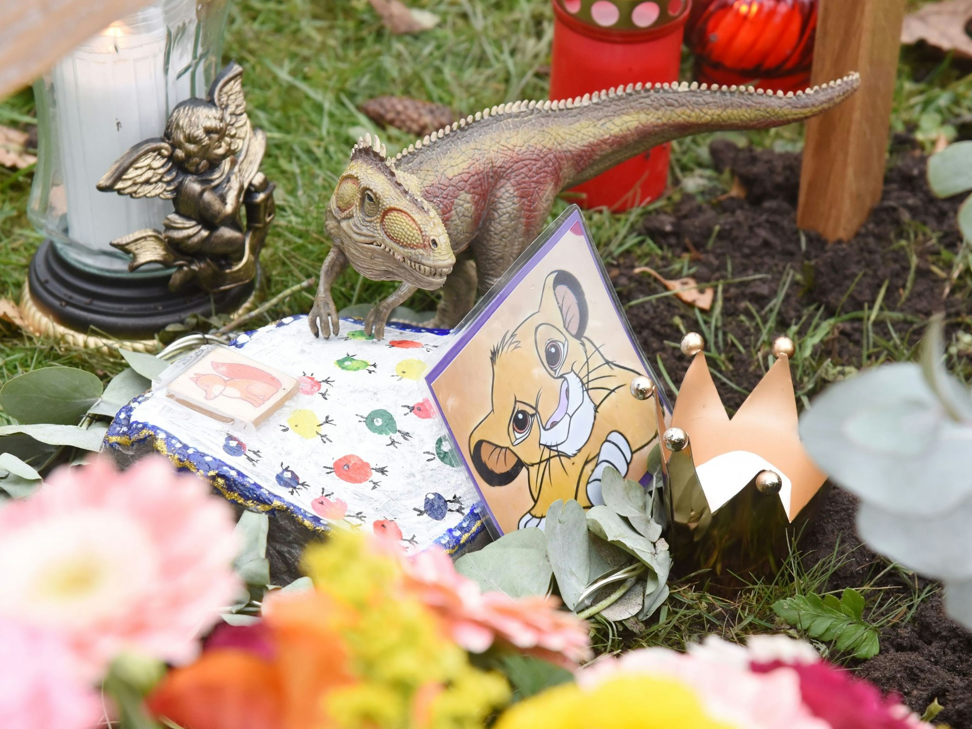 Das Grab von Derya und Kian auf dem Friedhof Chorweiler mit Blumen, Kerzen und Spielzeug
