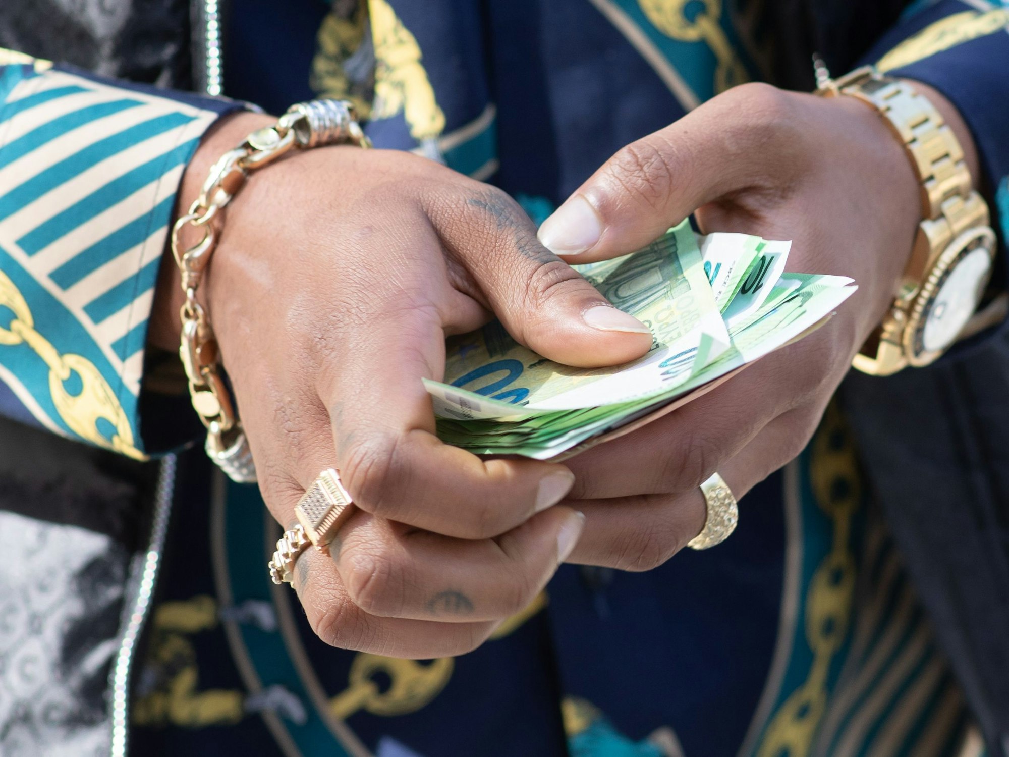 Ein Musiker und Rapper hält nach seinem Prozess vor dem Amtsgericht St. Georg ein Bündel Geldscheine.