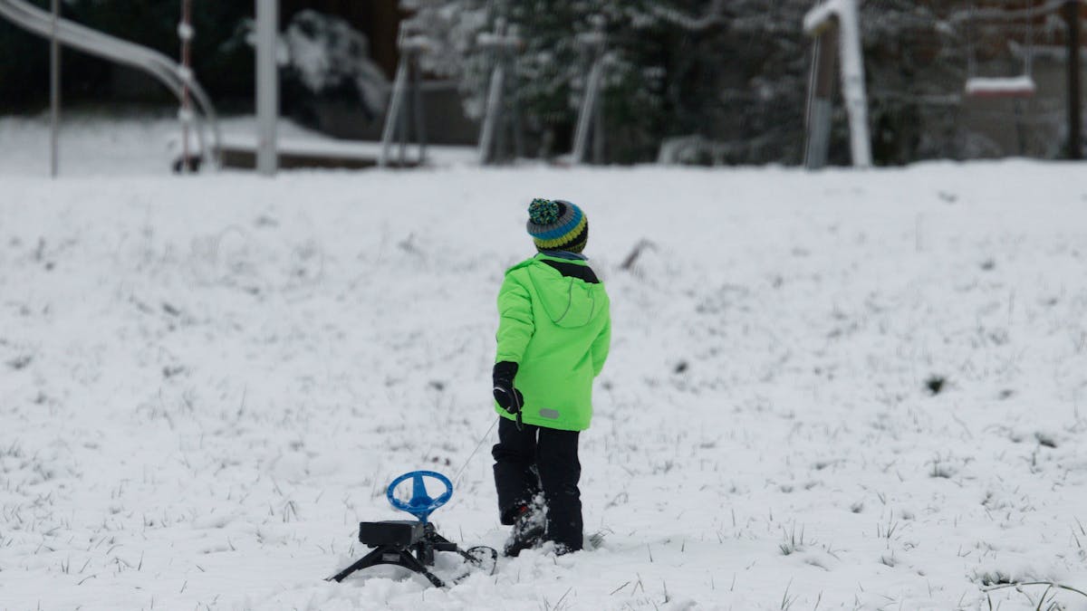 Ein Kind zieht neben der Skipiste Rauher Busch einen Schlitten über den Schnee.