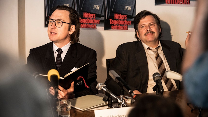 Szene aus Faking Hitler (RTL+): Gerd Heidemann (Lars Eidinger, l.) und Felix Bloom (Hans Jochen Wagner) präsentieren die Hitler-Tagebücher.