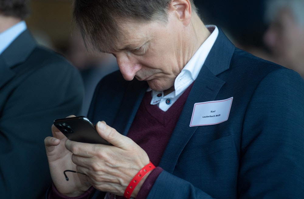 Karl Lauterbach schaut auf sein Smartphone
