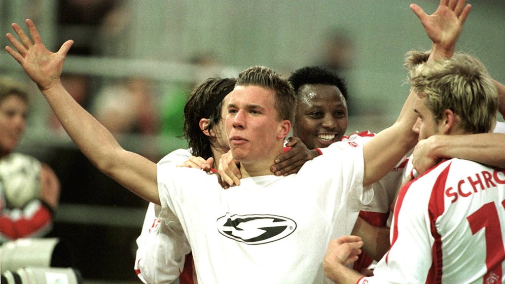 Lukas Podolski breitet beim Jubeln die Arme aus und wird umringt von seinen Mitspielern.