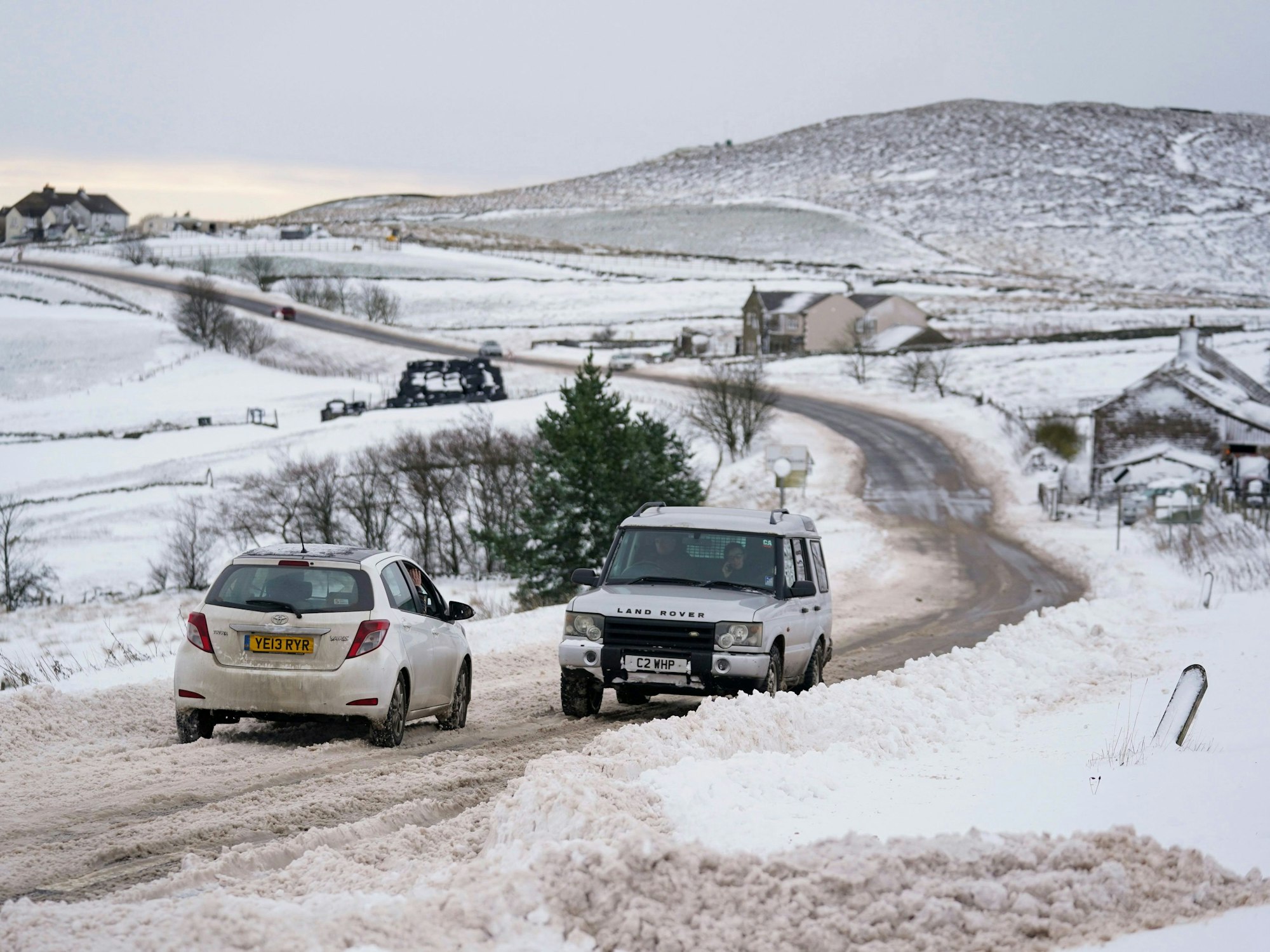 Vehicles travel tentatively on the snow-covered A53 close to Buxton in Derbyshire, amid freezing conditions in the aftermath of Storm Arwen, England, Sunday, Nov. 28, 2021.  (Jacob King/PA via AP)