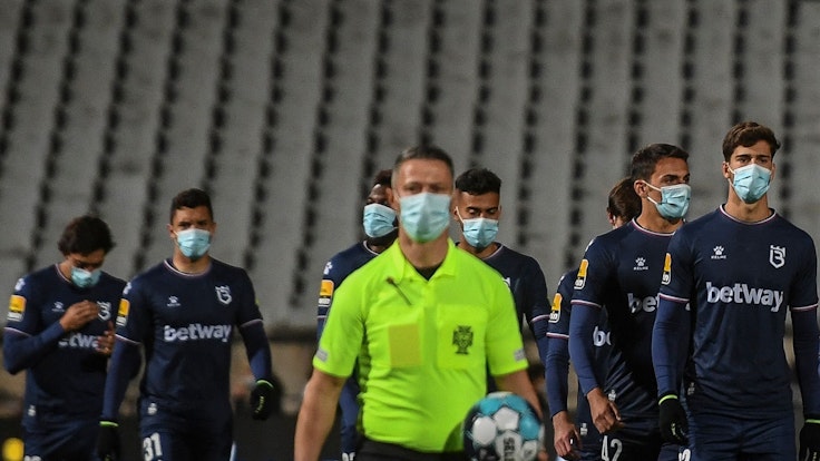 Die Spieler von Belenenses Lissabon und der Schiedsrichter gehen mit Masken auf den Platz.