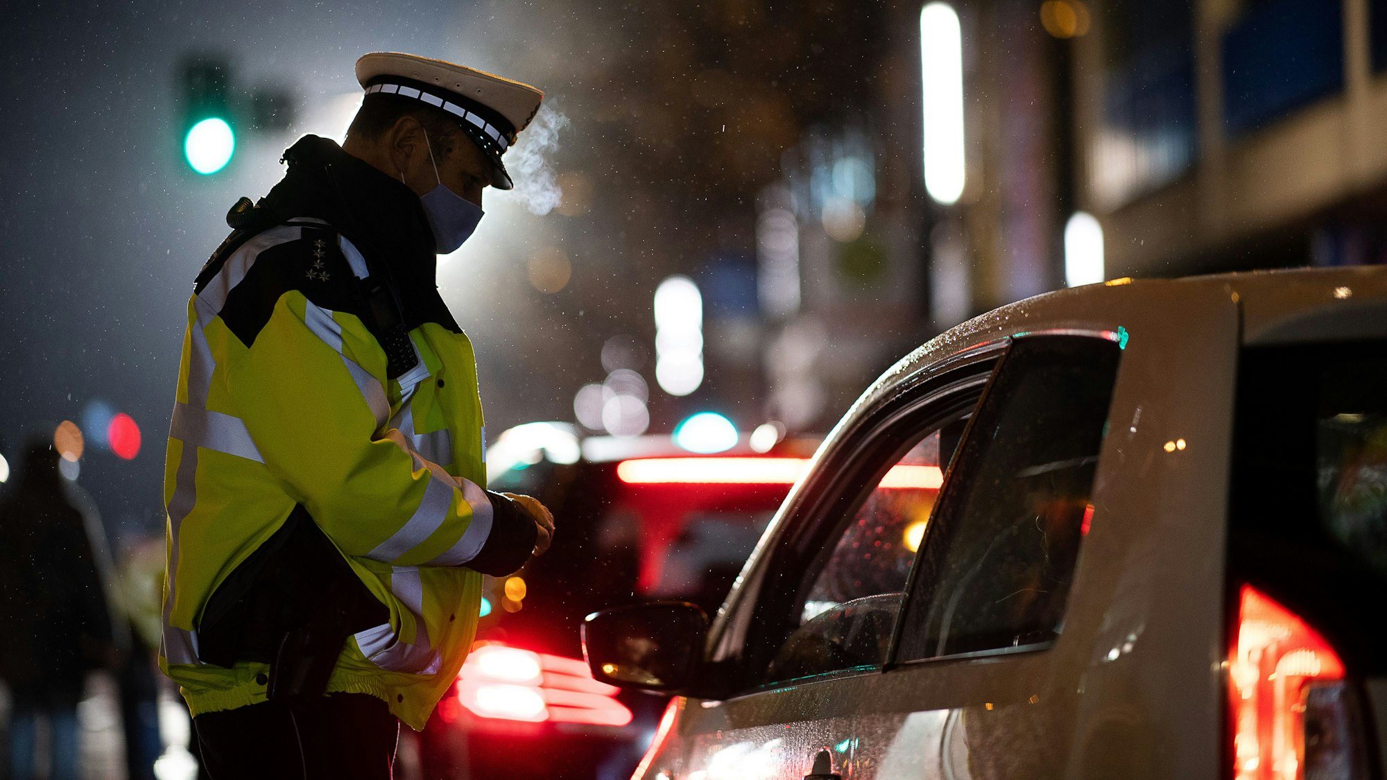 Das Symbolbild zeigt einen Polizeibeamten, der während einer Verkehrskontrolle mit einem Autofahrer spricht.