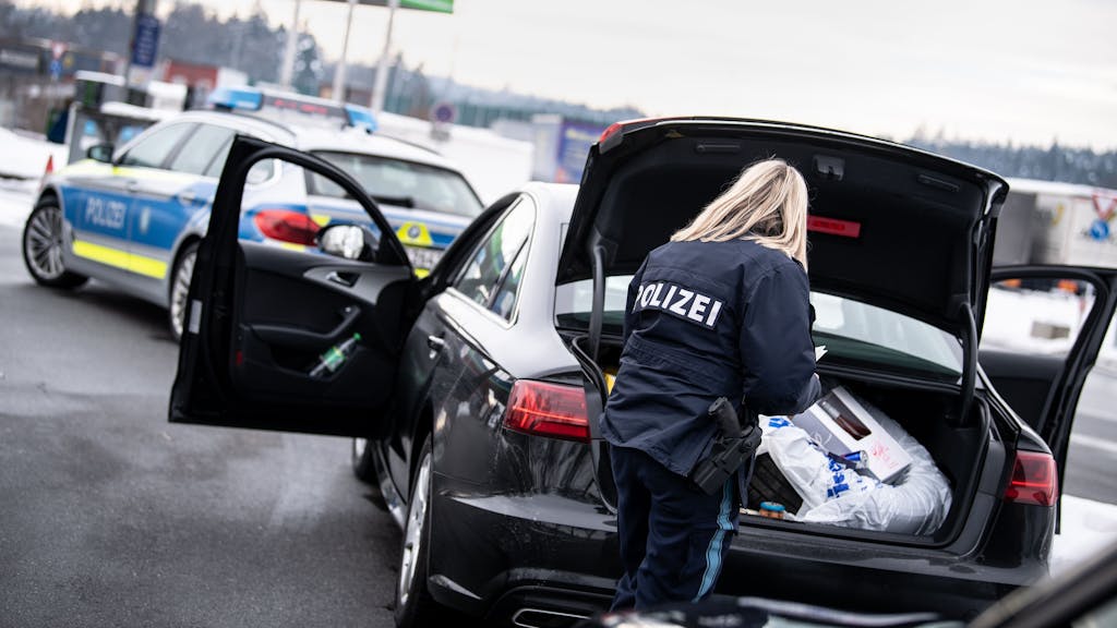 Eine Polizistin kontrolliert auf einem Rastplatz den Kofferraum eines Fahrzeugs.&nbsp;