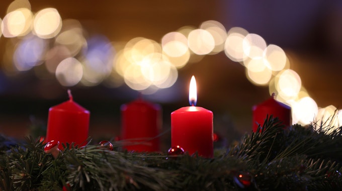 Auf dem Symbolfoto sieht man eine Kerze auf einem Adventskranz brennen.