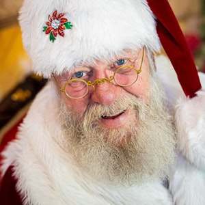 Weihnachtsmann Willi Dahmen sitzt in seinem Büro und lächelt in die Kamera.