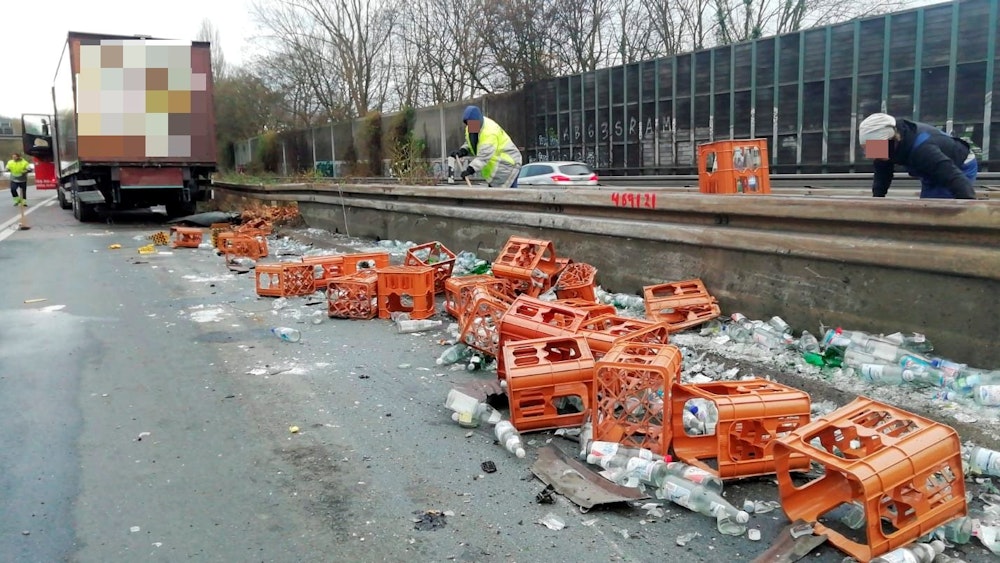 Nach einem Unfall auf der A555 liegen zahlreiche Getränkekisten und Flaschen an der Leitplanke.