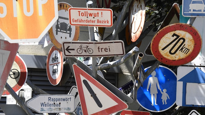 Ein Schilderbaum steht beim Tiefbauamt in Bayern. Dieser besteht aus ausrangierten Verkehrs- und Hinweisschildern.