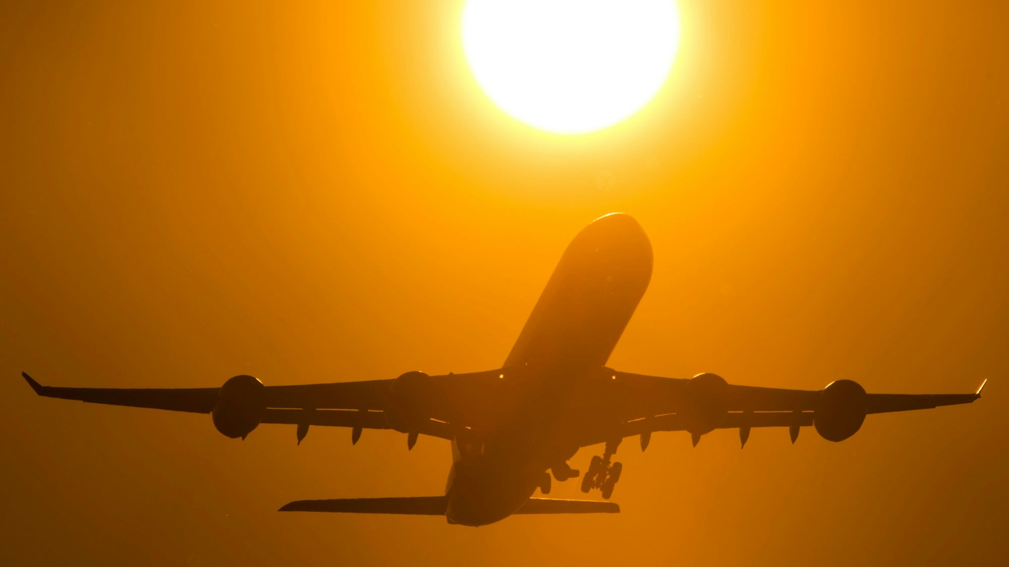 Ein Flugzeug startet in den Sonnenuntergang.