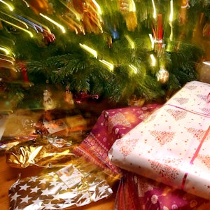 Weihnachtsgeschenke liegen unter einem geschmücktem Christbaum.
