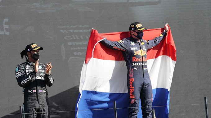 Der Zweitplatzierte Lewis Hamilton (l) aus Großbritannien vom Team Mercedes-AMG Petronas Formula One Team applaudiert während der Sieger Max Verstappen aus den Niederlanden vom Team Red Bull Racing Honda eine niederländische Fahne hält.&nbsp;