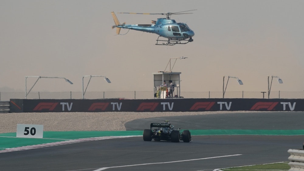 Ein TV-Hubschrauber fliegt über dem Rennwagen von Sebastian Vettel.