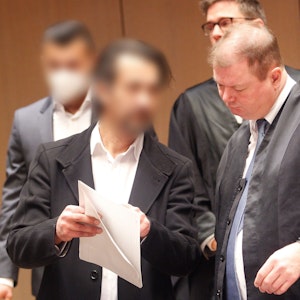 Zwei Männer stehen in Bochum vor Gericht, einer zeigt seinem Verteidiger ein Schriftstück.