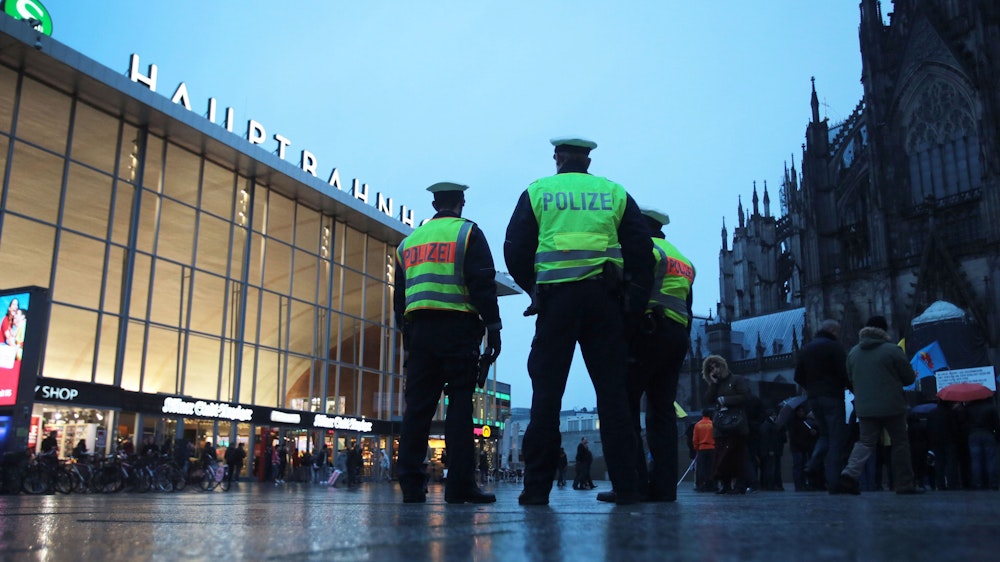 Drei Polizisten stehen in Köln vor dem Hauptbahnhof.
