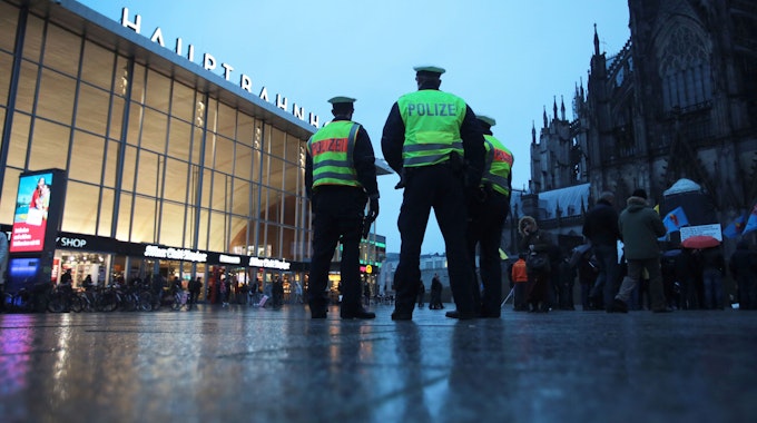 Drei Polizisten stehen in Köln vor dem Hauptbahnhof.