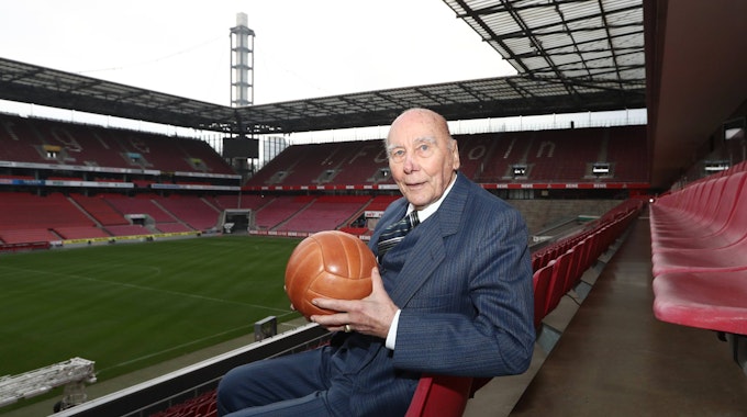 Horst Eckel sitzt mit einem alten Fußball im Stadion.