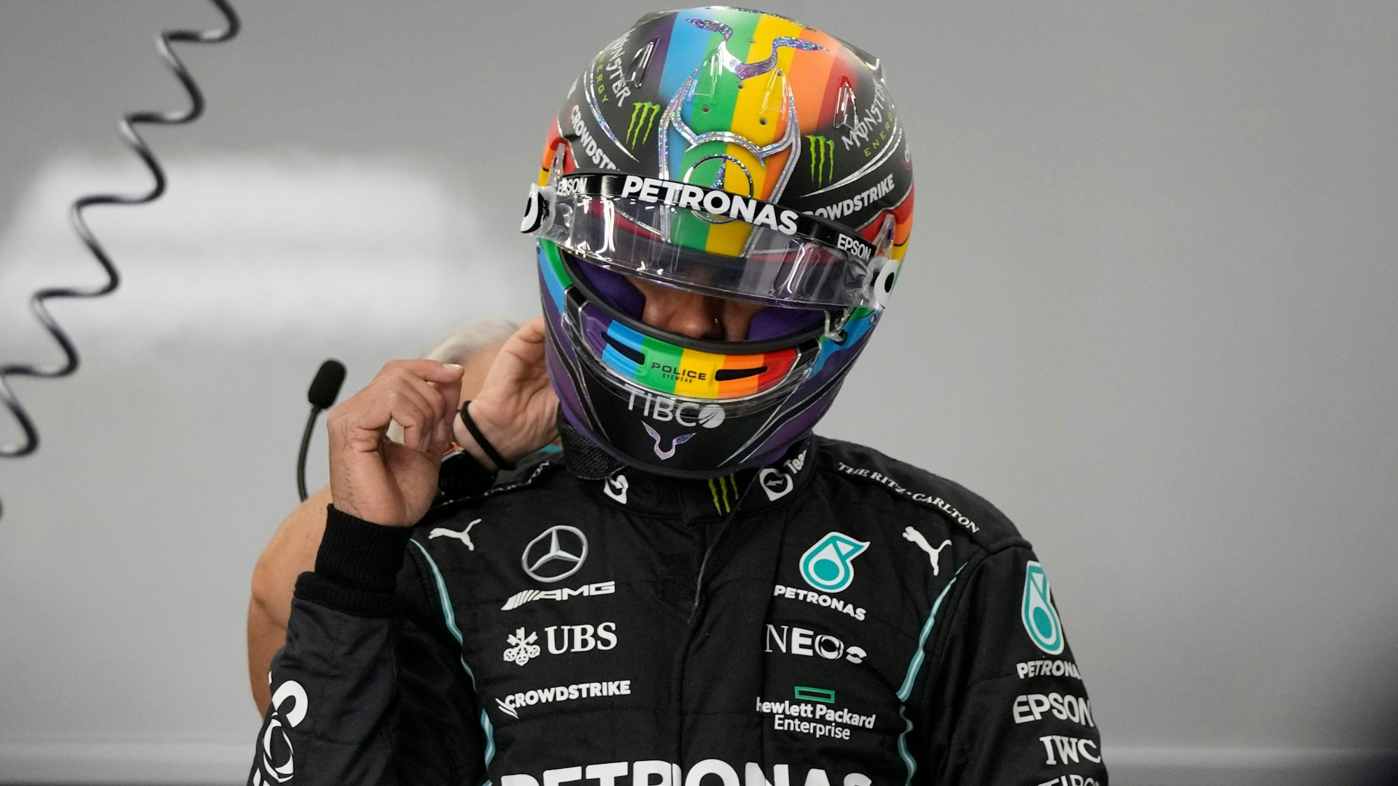 Lewis Hamilton steht in Rennmontur in der Box.