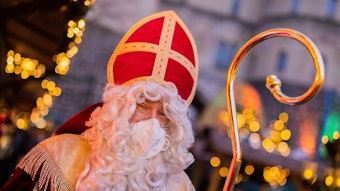 Stefan Dößereck, Nikolaus- und Weihnachtsmanndarsteller, trägt eine FFP2-Maske auf dem Weihnachtsmarkt «Nikolausdorf» auf dem Rudolfplatz.