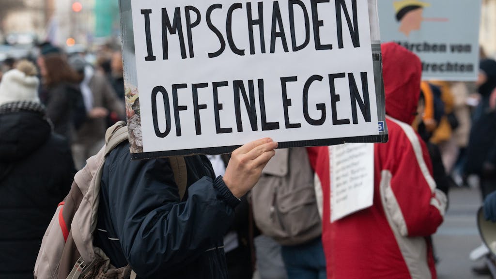 Teilnehmer einer Demonstration hält ein Schild mit der Auschrift "Impschäden offenlegen". Mehr als zweitausend Impfgegner, Coronaleugner und Querdenker demonstrieren in der Innenstadt von Frankfurt am Main.