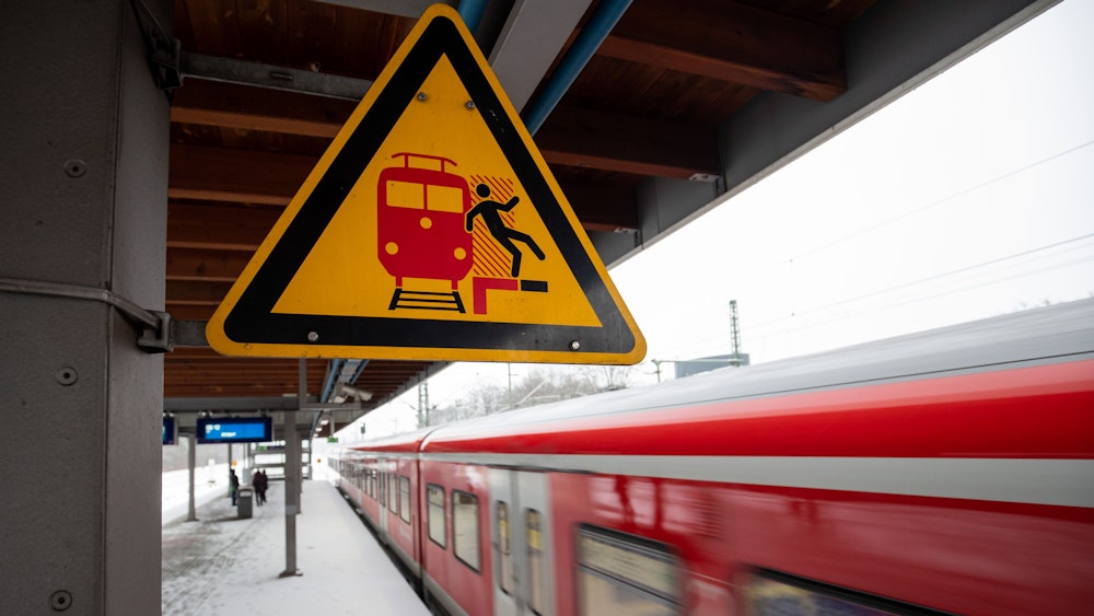 Das Symbolbild zeigt ein Schild, das an einem S-Bahnsteig vor der Gefahr, auf das Gleis zu fallen, warnt.